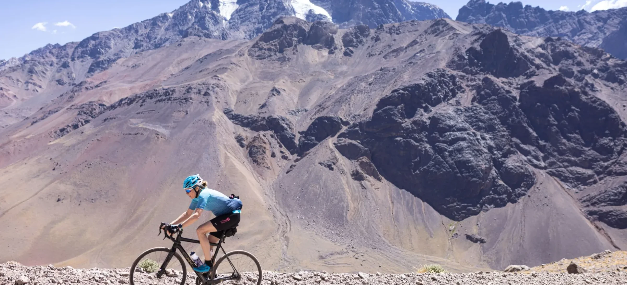 Cyclist riding along rocky path next to mountains