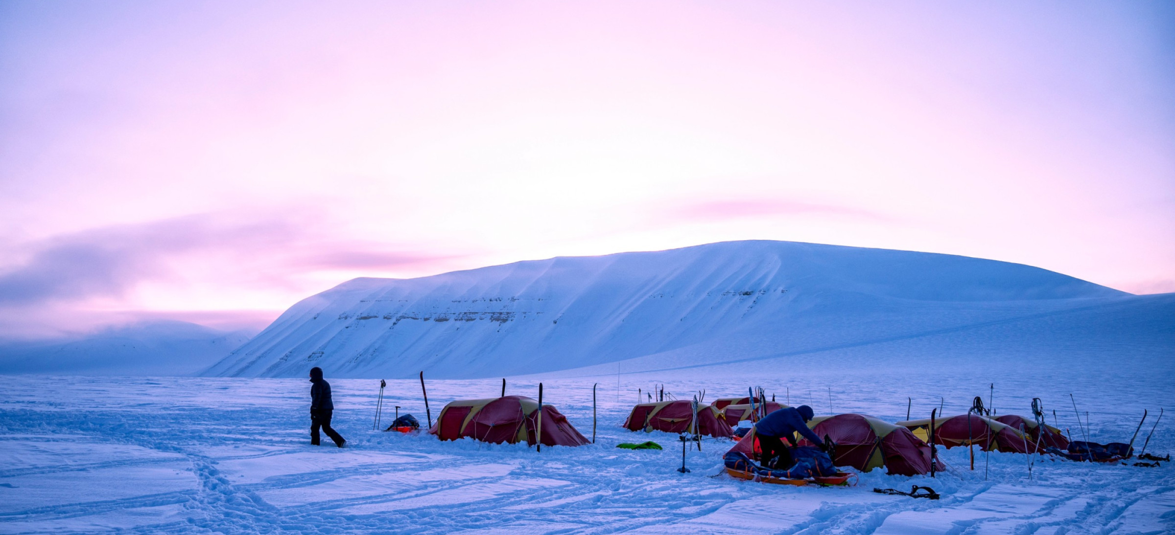 Participant walking away from tents pitched in deep snow