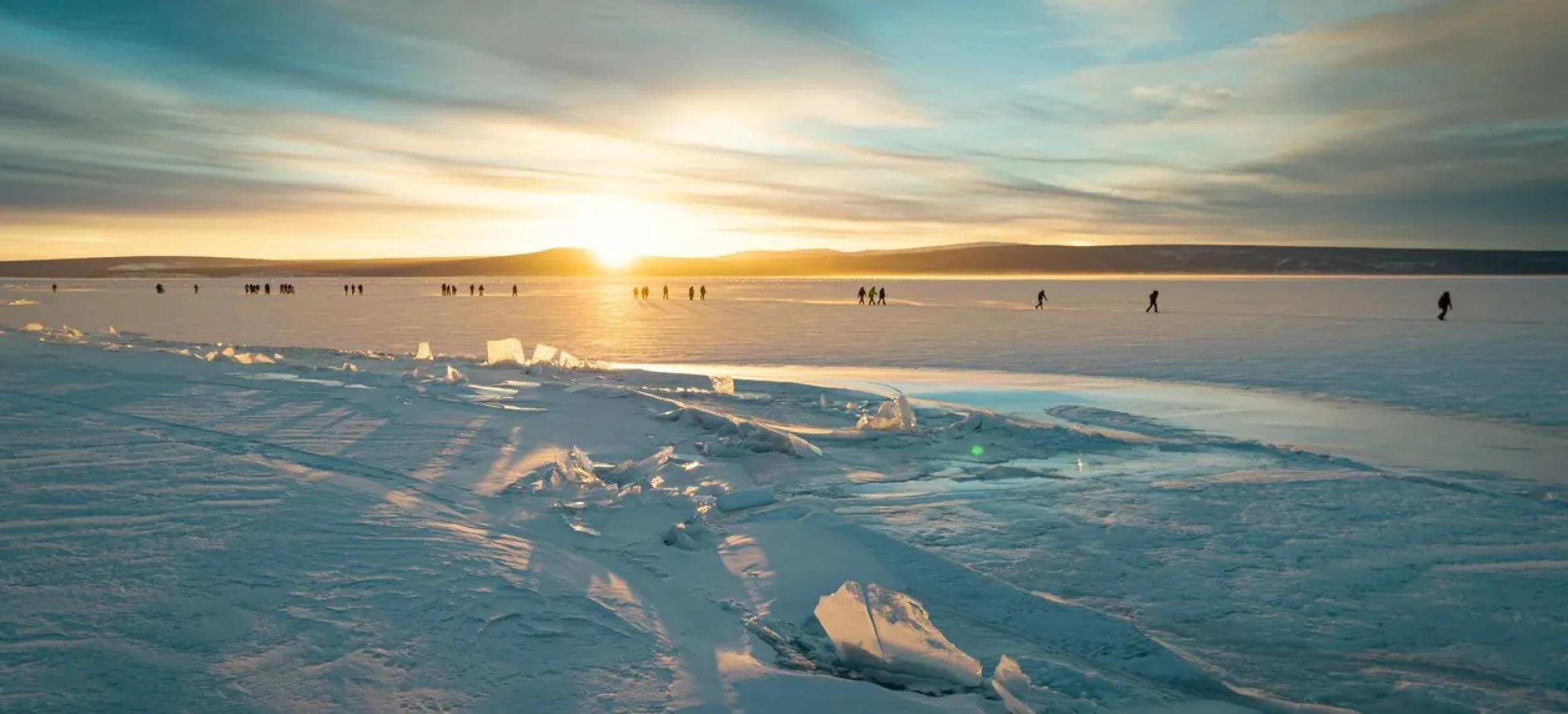 Participants walking on snow with orange sky behind them
