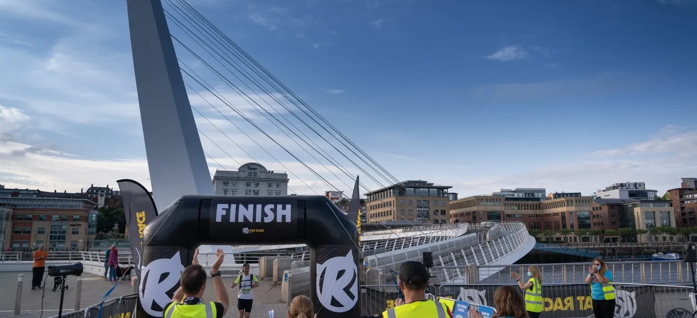 Volunteers clapping as participant runs through finish arch