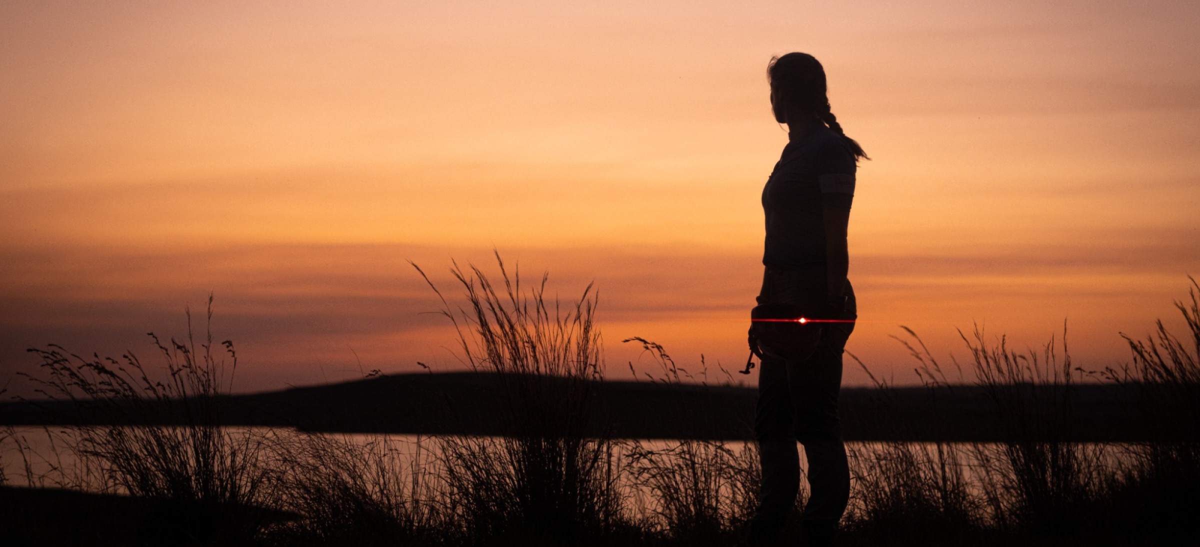 Woman stood by water at sunset