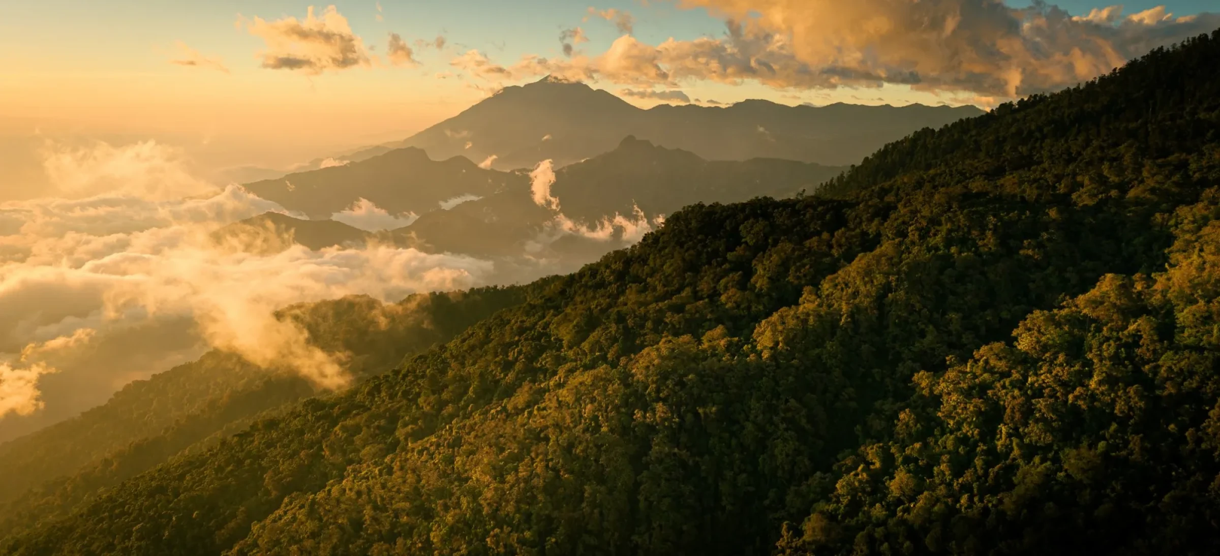 Colourful cloudy sky with mountains in the background and tree-covered hills