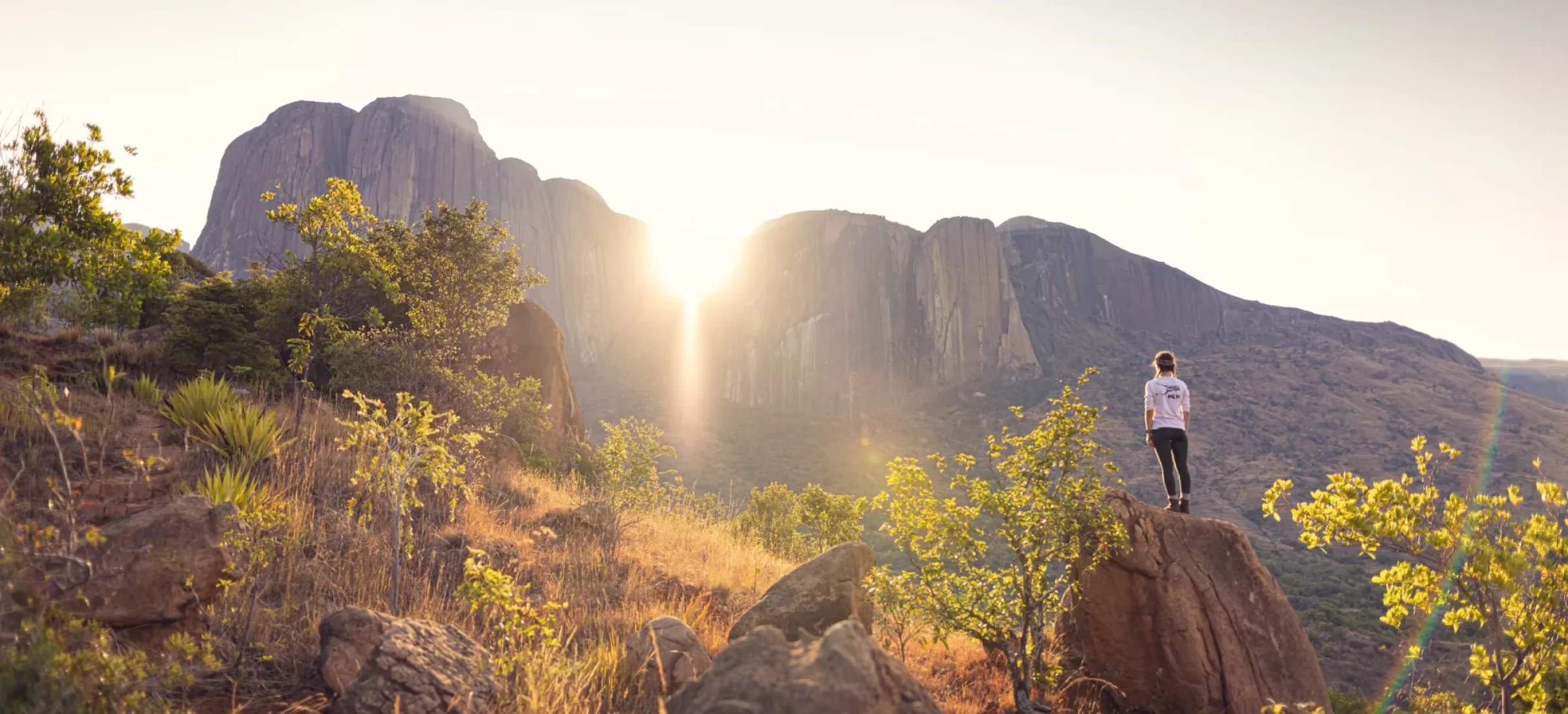 Woman stood on rocks and looking up at mountains
