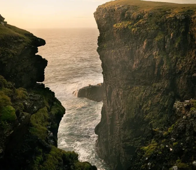 People stood on cliff with colourful sky behind
