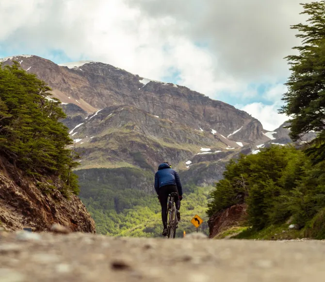 Cyclist riding along road, towards mountains