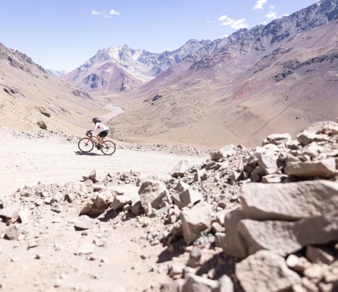 Cyclist riding along dusty terrain surrounded by mountains