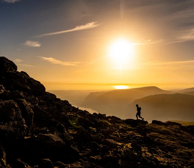Participant running up rocky slope in sunset