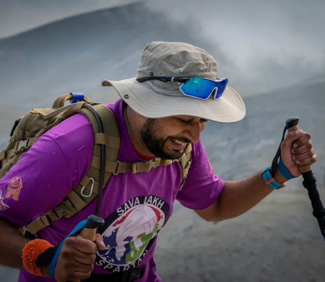 Man using trekking poles and hiking up rocky mountain