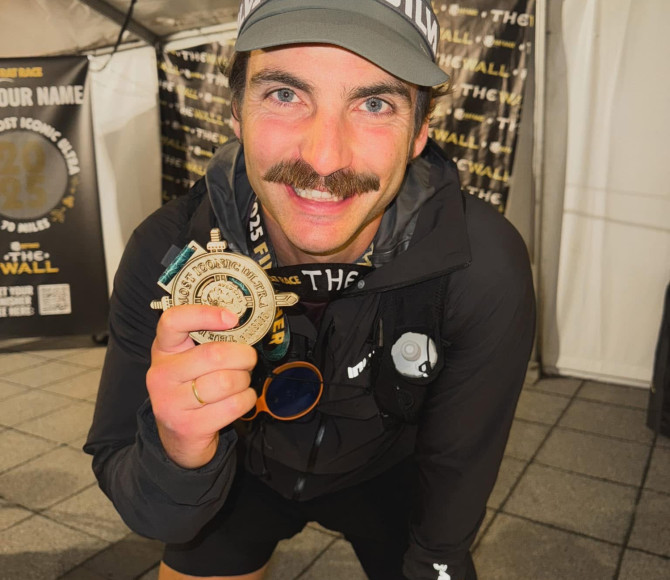 Man smiling and holding up medal