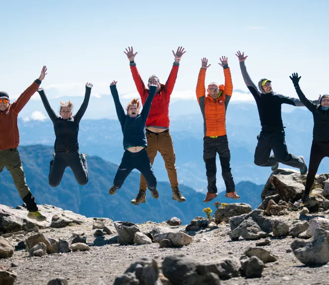 Participants wearing colourful clothing and jumping with their hands in the air