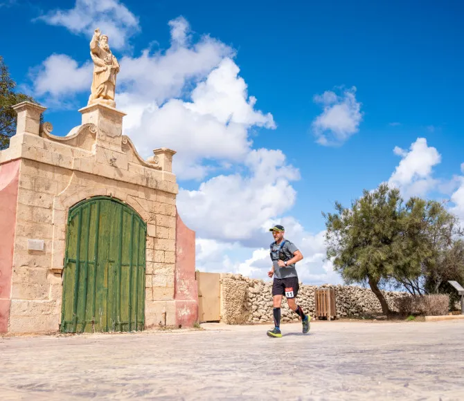 Man running past grand building entrance in sunshine