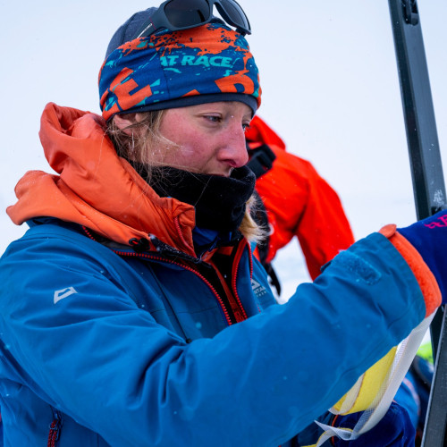 Woman holding equipment in a snowy, white environment