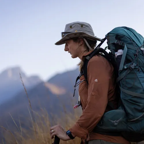 Woman hiking through grassland wearing a rucksack