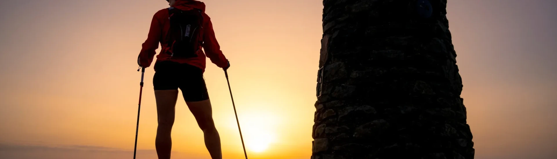 Woman standing at top of Yr Wyddfa at sunset