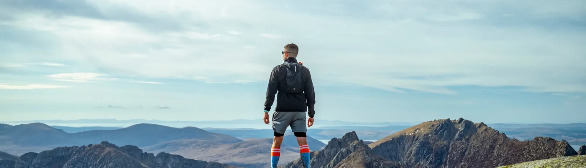 Man stood on rocks, looking out at view