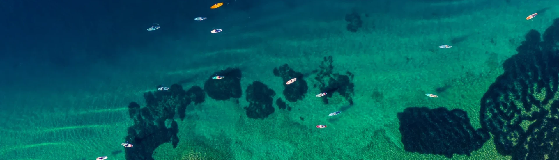 A group of participants kayak through shallow turquoise waters