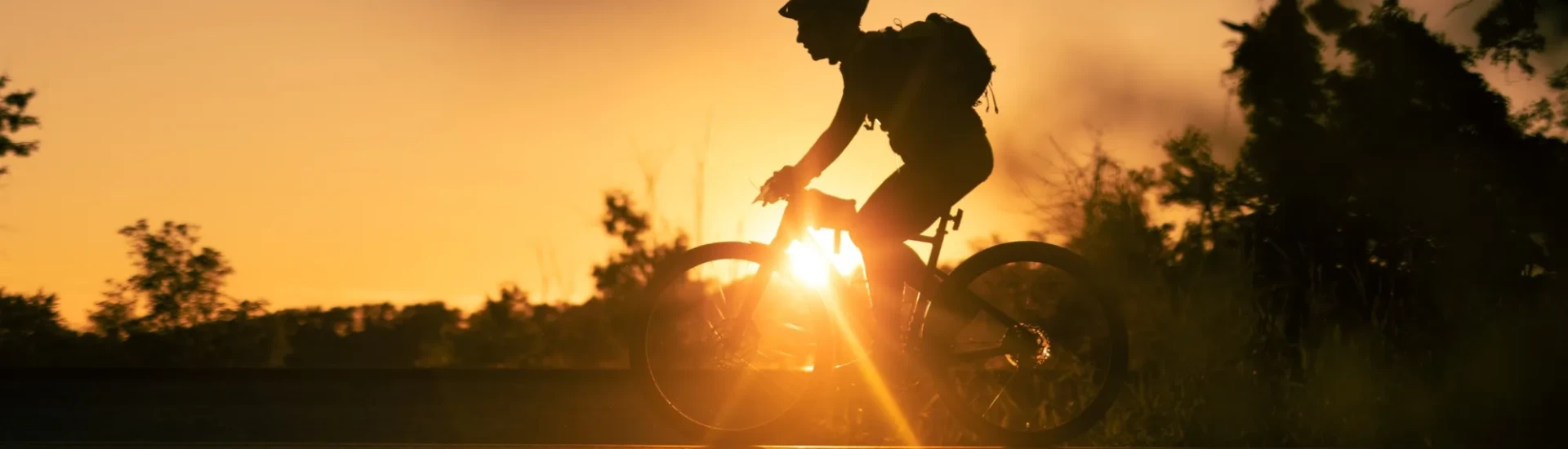 Silhouette of cyclist and bike with colourful sky behind