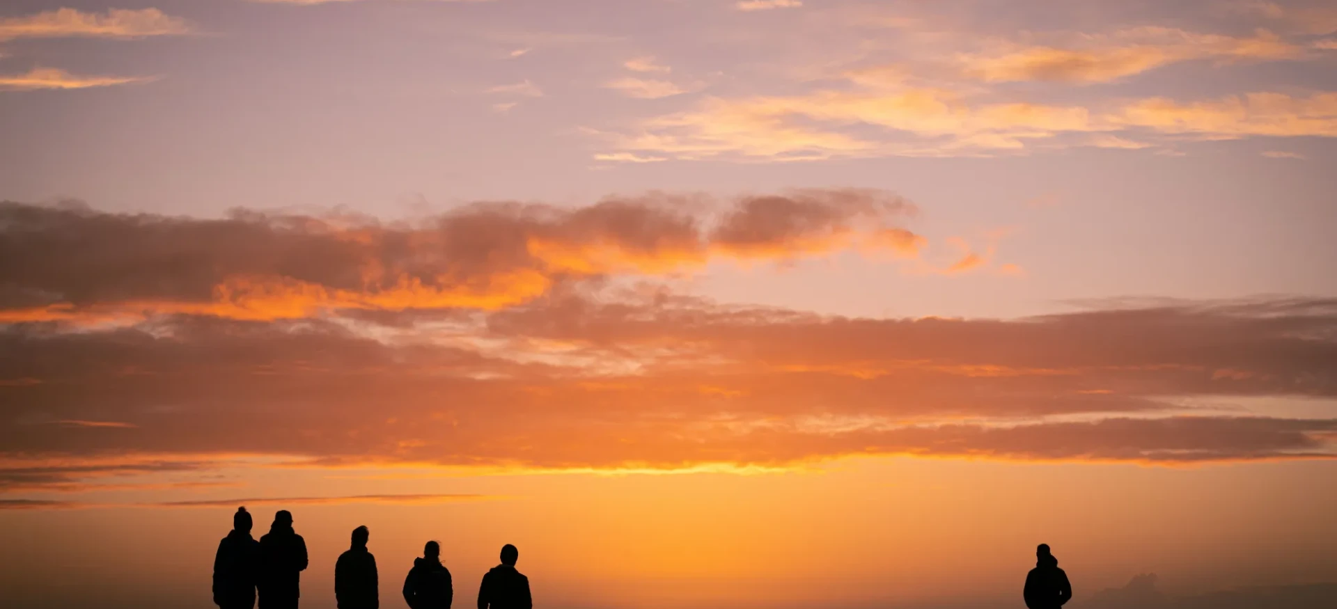 Silhouettes of participants looking out to colourful sky