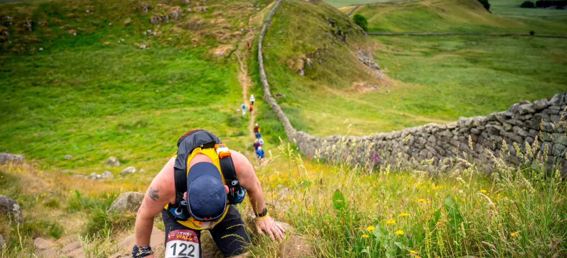 Man climbing up hill next to wall