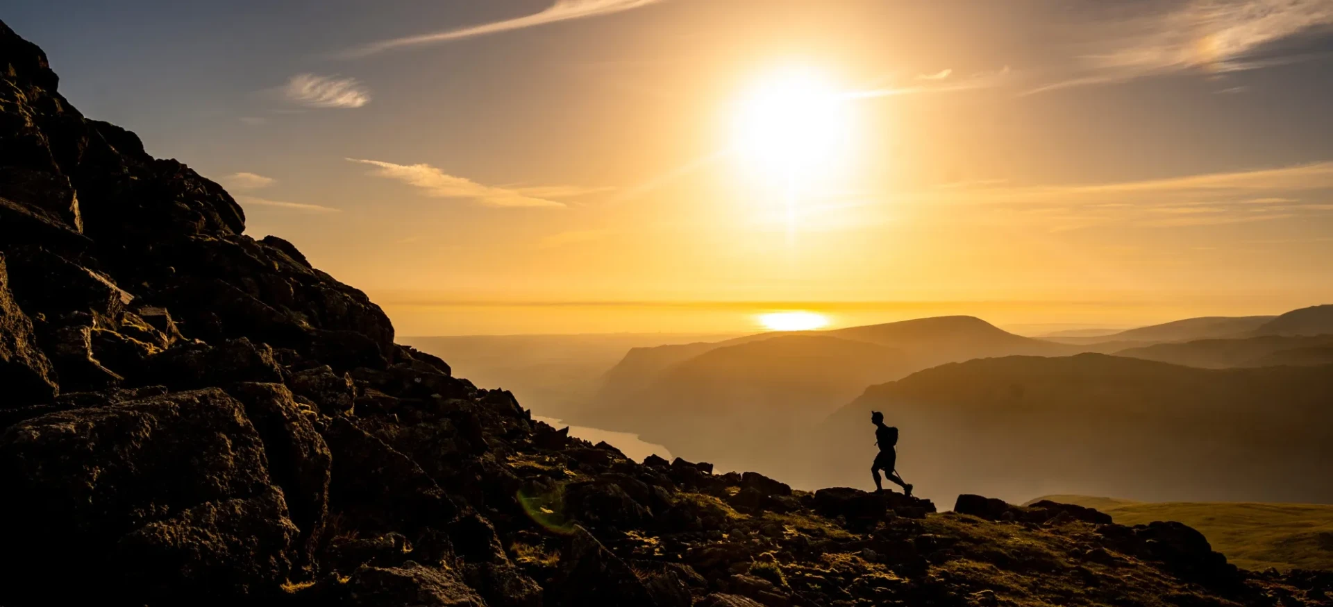 Participant running up rocky slope in sunset