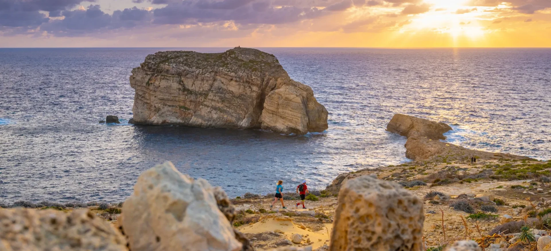 Participants running along rocky, coastal track