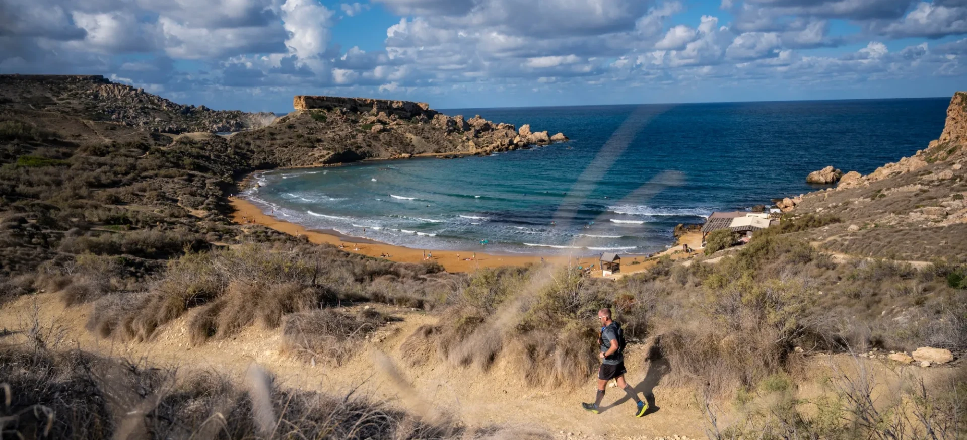 Man running along sandy and rocky coastline
