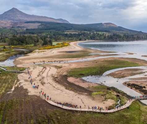 People running along beach with mountain in background