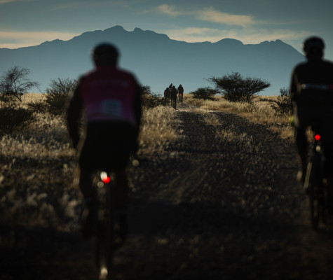 Cyclists riding along track with mountains ahead