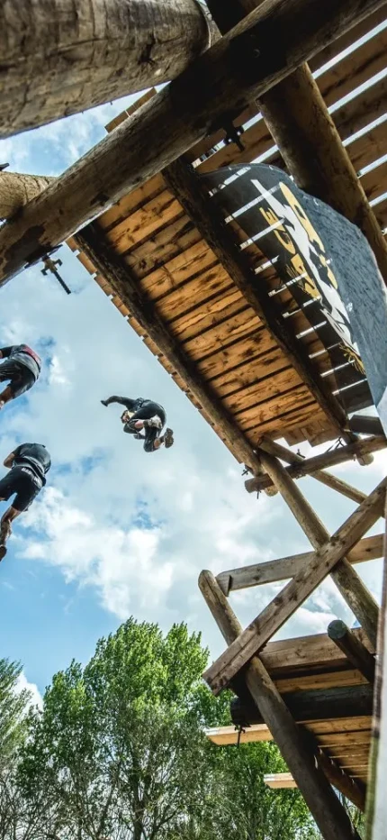 Participants jumping from a wooden ledge, with bright, blue sky above them