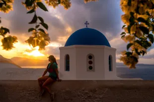 Woman sat on wall with white and blue building behind her