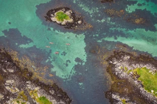 Aerial view of participants kayaking through clear, blue water