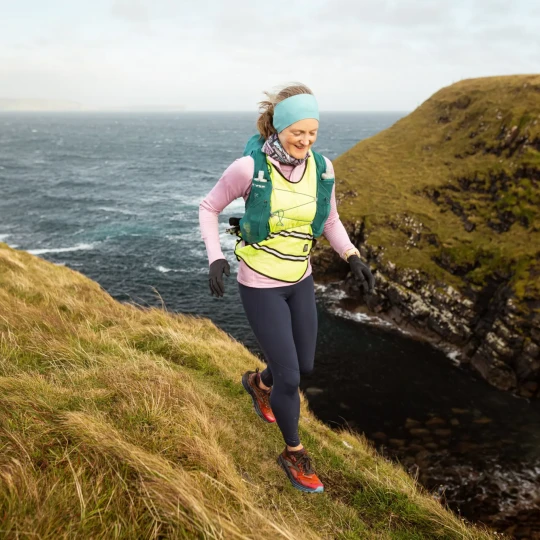 Woman running along grassy coastline