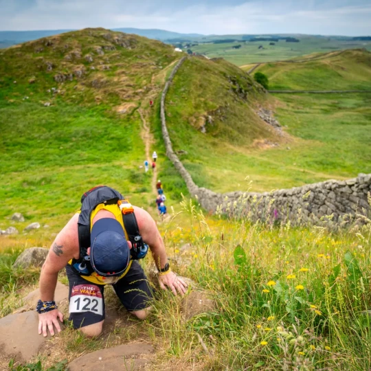 Man climbing up hill next to wall