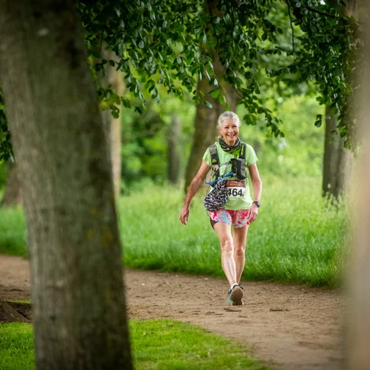 Woman smiling and walking on path through trees
