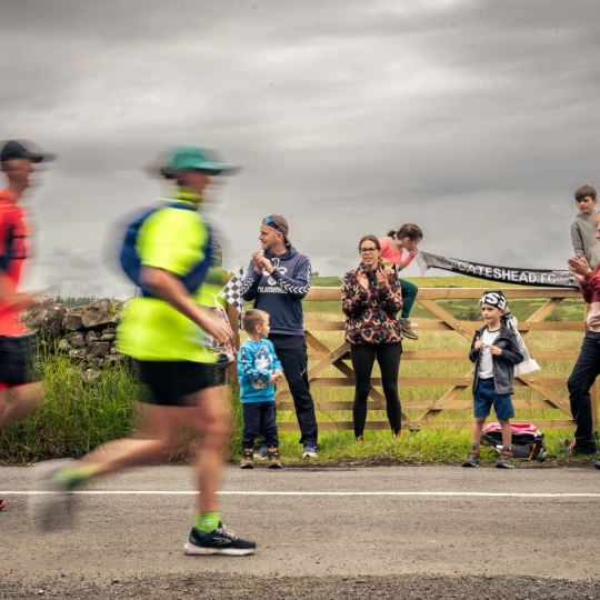 People running and spectators clapping and cheering
