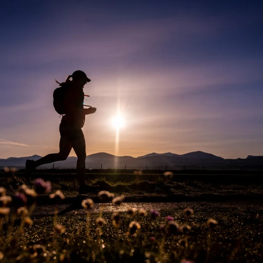 Woman running on track with colourful dark sky above her