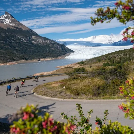 Cyclists riding around bend and snowy mountains in background