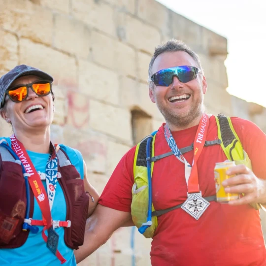 Man and woman holding canned drinks and smiling in the sunshine
