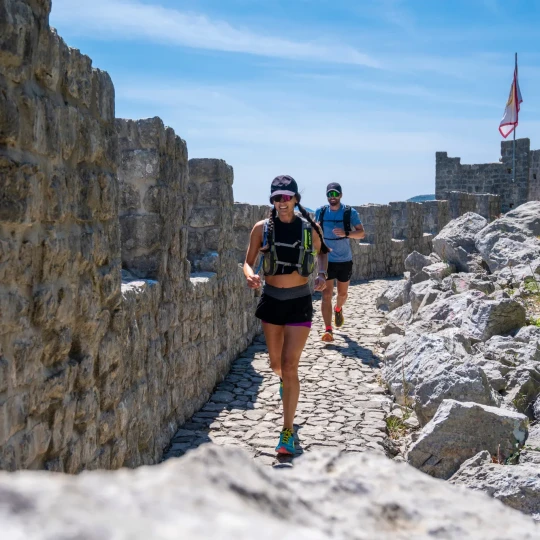 A man and a woman run next to a wall