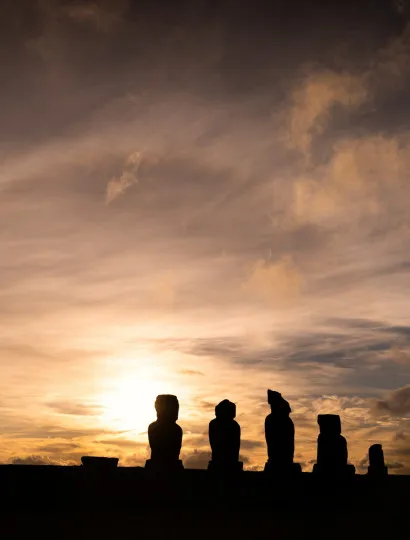Silhouettes of statues and a colourful sky behind them