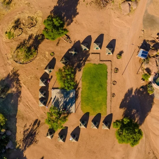Aerial view of tents, sand and sparse trees