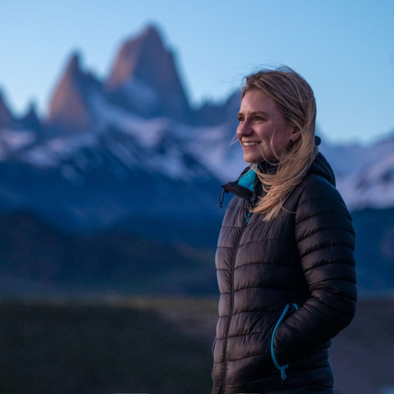Woman stood infront of snow-covered mountains and smiling