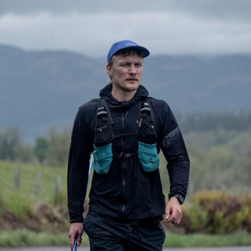 Man walking along road with trees and fields behind him