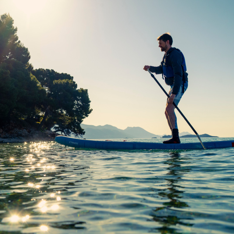 Man paddle boarding across sea