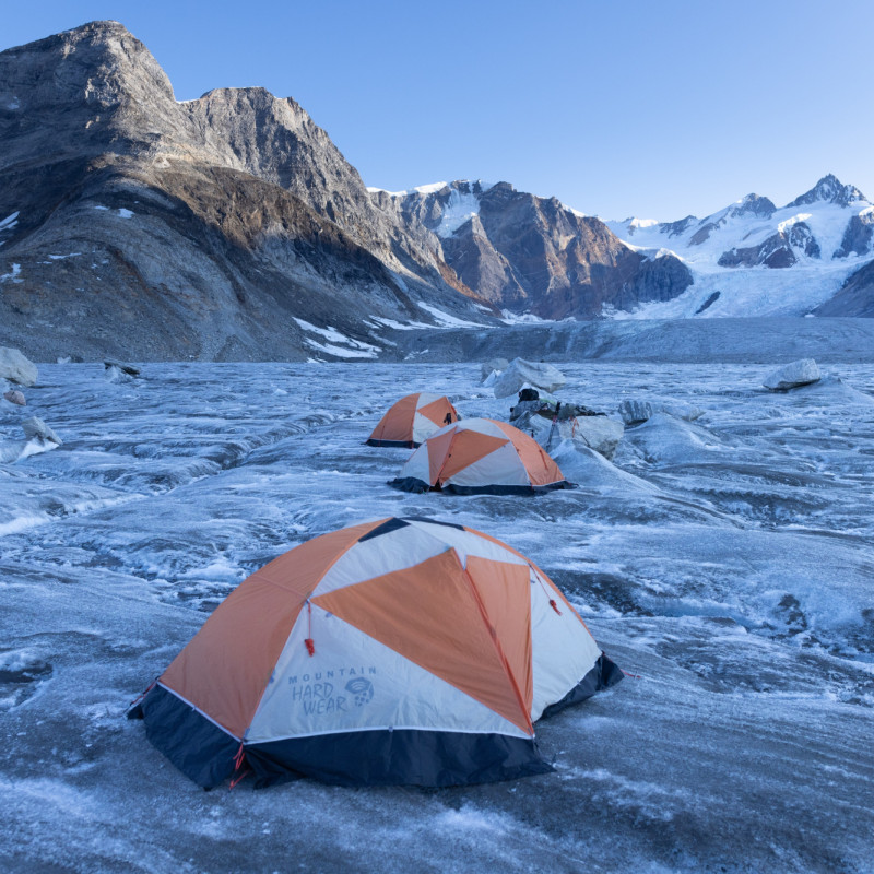 Tents pitched on snow and ice with mountains in the background