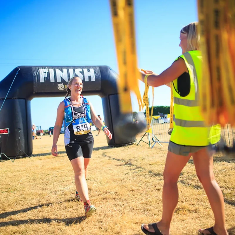 Volunteer getting ready to place medal on women's neck at finish