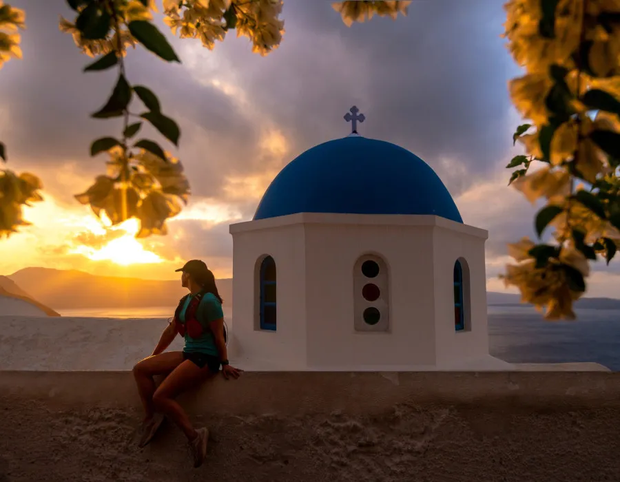 Woman sat on wall with white and blue building behind her
