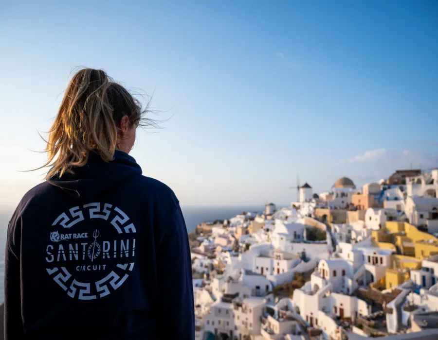 Woman wearing Santorini hoodie and looking down onto white buildings