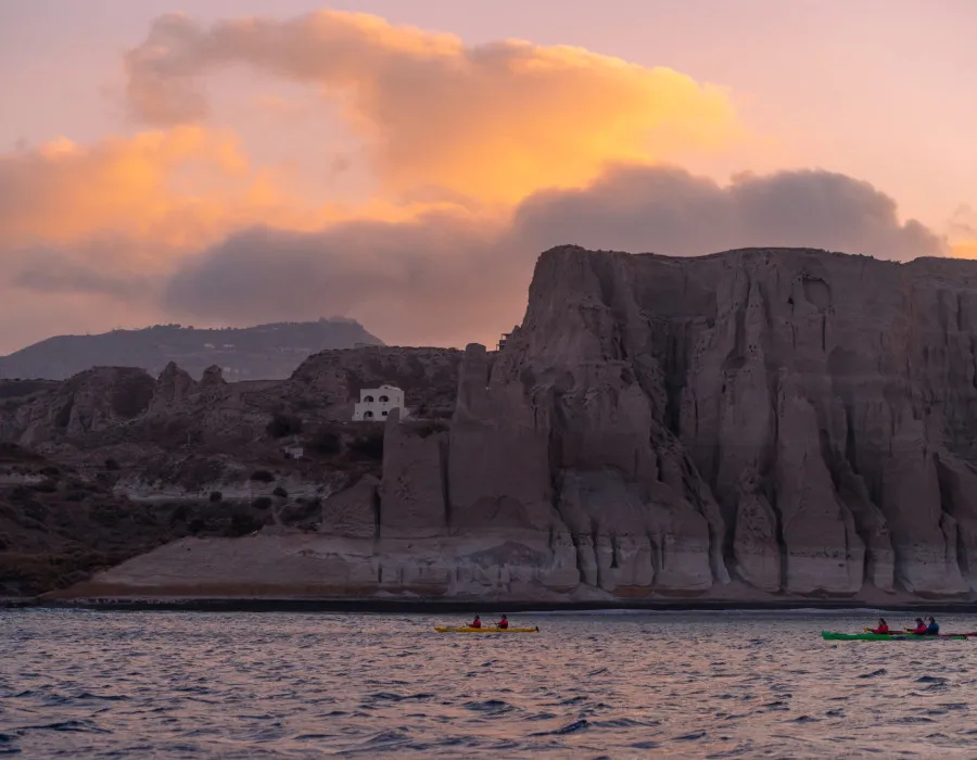 Participants kayaking through sea at sunset