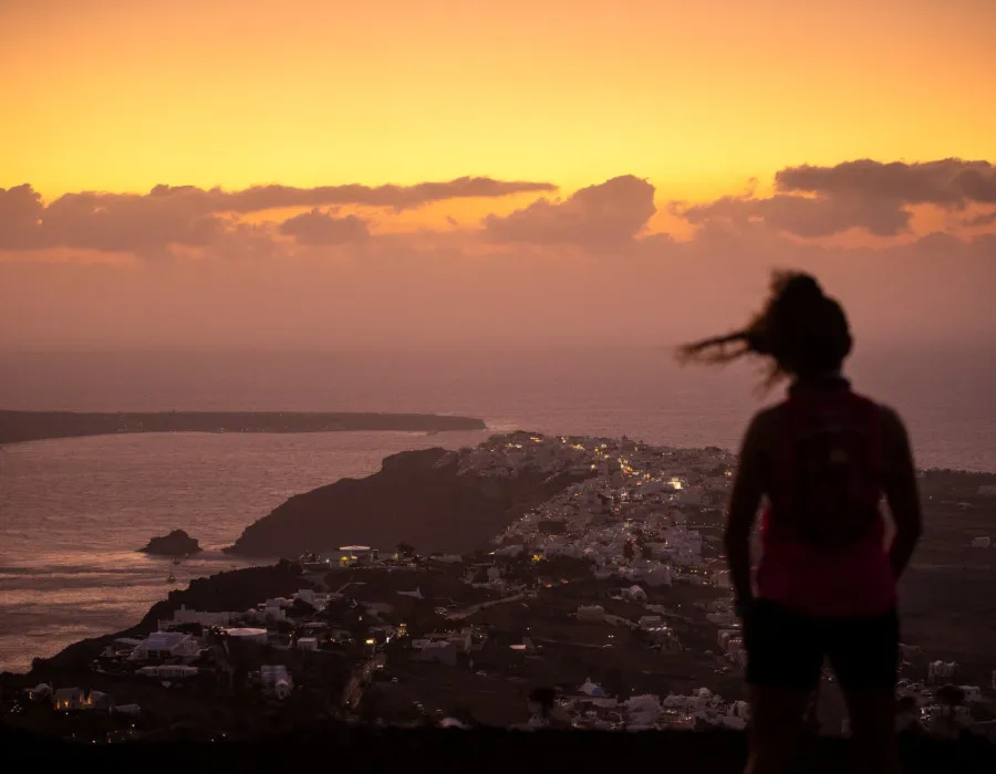 Woman stood looking out over buildings at sunset